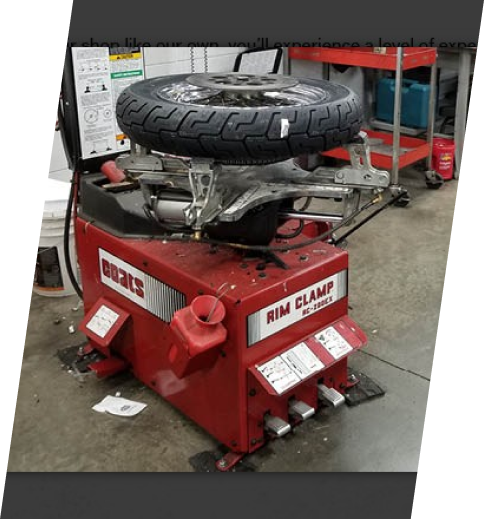 A tire changer is shown with the wheel on top.